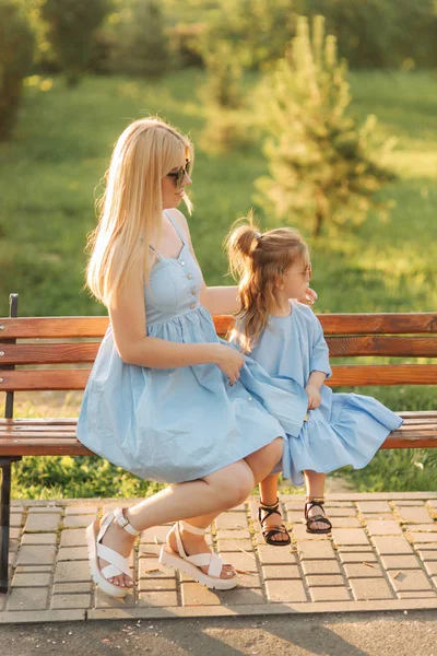 Anne ve küçük kızı parkta bir bankta oturmuş