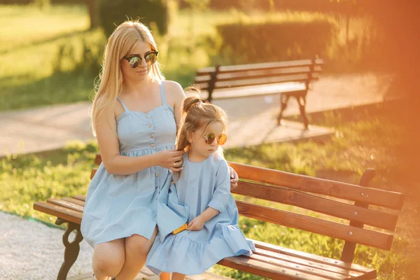 Maminka a jeho malá dcera sedí na lavičce v parku — Stock fotografie