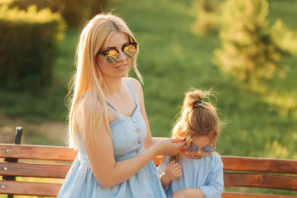 Anne ve küçük kızı parkta bir bankta oturmuş