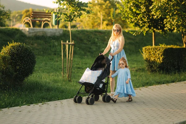 küçük kızı anne bebek arabası itme yardımcı olur. Mutlu bir aile