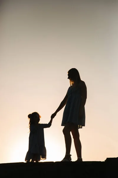 Anne ve küçük kızı silüeti — Stok fotoğraf