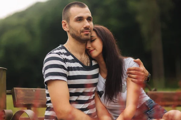 Парень и девушка наслаждаются друг другом в романтической атмосфере и сидят на лавочке — стоковое фото