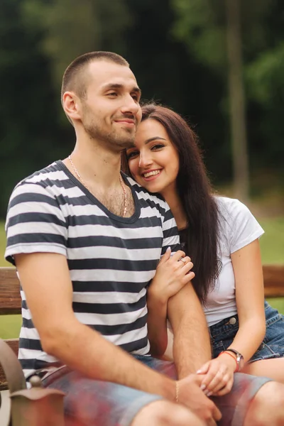 Ein Kerl und ein Mädchen genießen einander in romantischer Atmosphäre und sitzen auf der Bank — Stockfoto