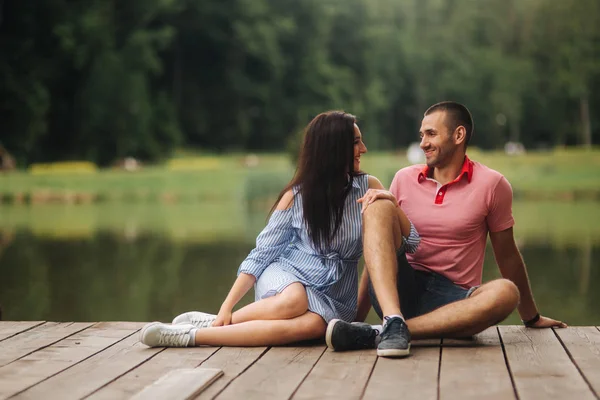 Mann und Mädchen genießen einander in romantischer Atmosphäre, sitzen auf der Seebrücke — Stockfoto