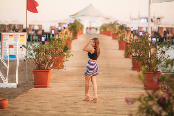 Vonzó lány séta a mólón, a tenger közelében napnyugta időpontja — Stock Fotó