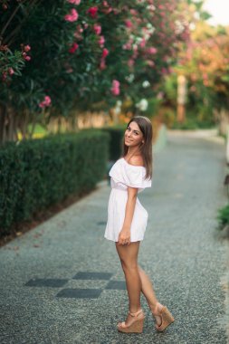 Seksi Bayan beyaz elbise ayakta çiçekler yakınındaki