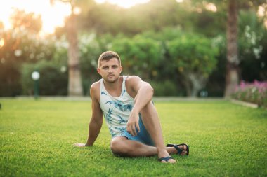 Gülümsüyor adam şort ve gömlek yaz aylarında park yakınlarında yürür