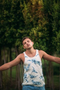 Gülümsüyor adam şort ve gömlek yaz aylarında park yakınlarında yürür