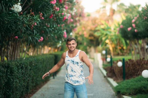 Hombre sonriente en pantalones cortos y camisa en verano camina cerca del parque — Foto de Stock