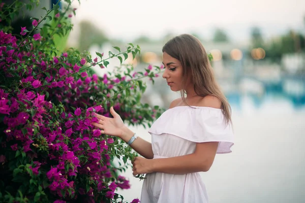 Genç ve güzel kız yaz şehir ayakta yakınındaki çiçek — Stok fotoğraf
