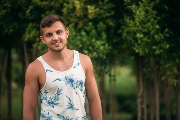 Hombre sonriente en pantalones cortos y camisa en verano camina cerca del parque — Foto de Stock