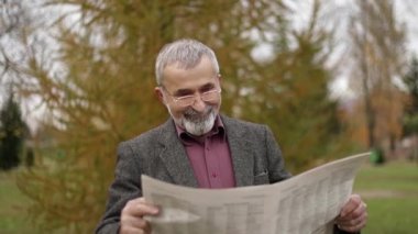 Parkta gri ceketli güzel sakallı güzel dede ve bir gazete okuyor