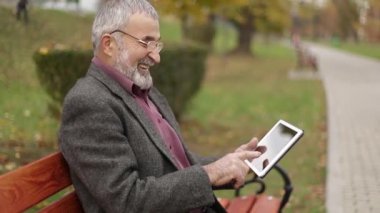 Büyükbaba kullanın parkta bankta oturan bir tablet