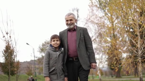 Grand-père et son petit-fils passent du temps ensemble dans le parc. Ils marchent dans le parc et se réjouissent — Video