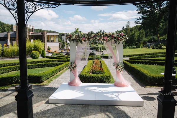 Weddind decoration on open air. Floral decor of a beautiful white arch. Beautiful beckground view of trees — Stock Photo, Image