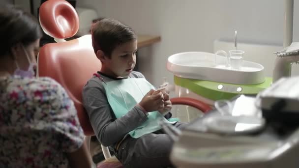 Medicina, odontología y concepto de salud dentista femenina con niño paciente en la clínica dental silla de ajuste — Vídeo de stock