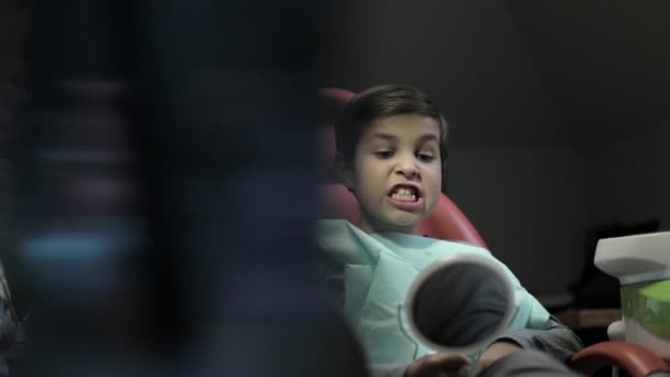 Geneeskunde, tandheelkunde en healthcare concept - vrouwelijke tandarts met kid patiënt op tandheelkundige kliniek stoel aan te passen — Stockvideo