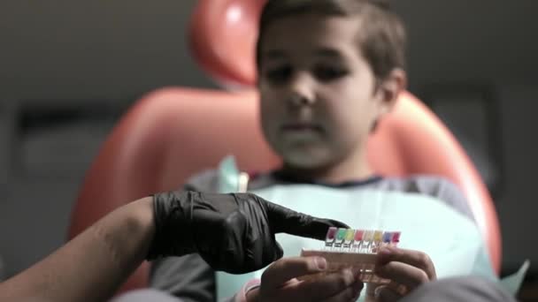 Um menino visita um dentista, uma mulher médico trata uma criança dentes — Vídeo de Stock