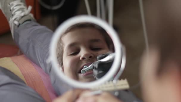 Um menino visita um dentista, uma mulher médico trata uma criança dentes — Vídeo de Stock