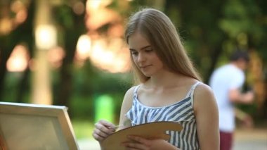 Güzel kız sanatçı parkta duran ve palet boya ile tutarak