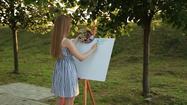 Gyönyörű lány művész állandó a parkban, és a gazdaság a palettán, a festékek — Stock videók
