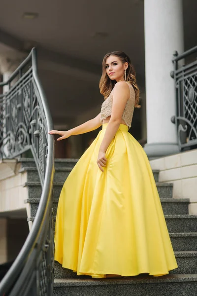 Beautiful girl with makeup and hairstyle is standing on the steps — Stock Photo, Image