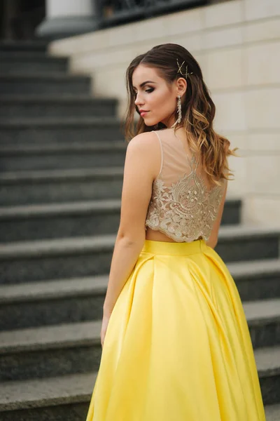 Beautiful girl with makeup and hairstyle is standing on the steps — Stock Photo, Image