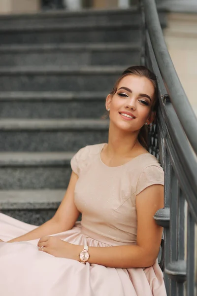 Modèle de mode sis dans les escaliers près de l'hôtel. Jeune fille sourire — Photo