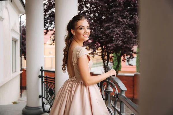 Modelo con gran pie vestido de noche junto al restaurante. Brunettegirl tiene un hermoso estilo de cabello — Foto de Stock