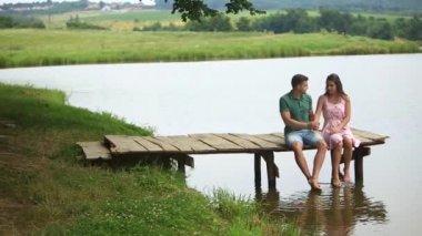 İskeleye yakın göl güzel youn çift otur. Romantik bir atmosfer