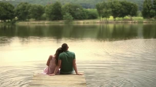 Vackra youn par sitta på bryggan vid sjön — Stockvideo