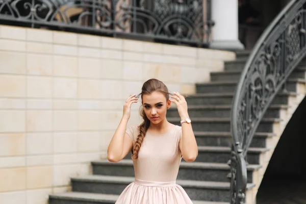 Model mit brünetten Haaren in einem puderfarbenen Kleid und mit Abendschminke — Stockfoto