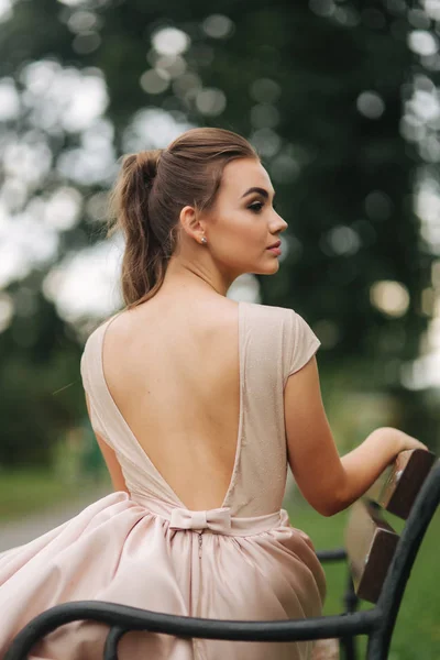Schickes Glamourmodel sitzt im Abendkleid auf Bank — Stockfoto