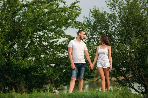 Sortir ensemble dans le parc. Couple d'amour debout ensemble sur l'herbe près du lac. Romance et amour — Photo