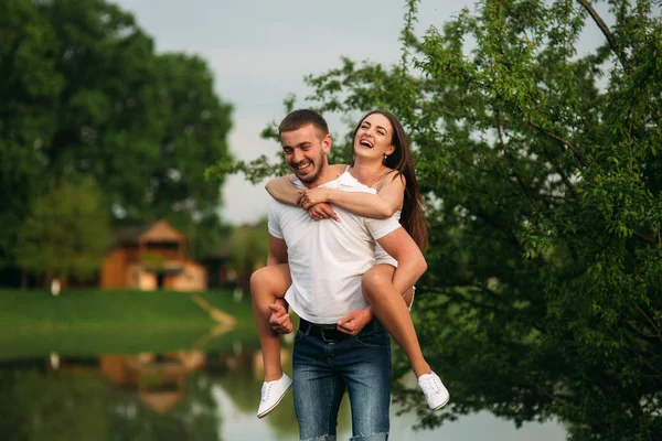 Due persone si divertono. Ragazza e ragazzo corrono vicino al lago — Foto Stock