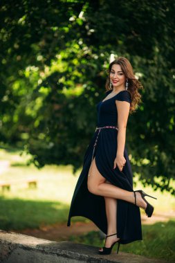 Mavi elbiseli güzel bir kız parkta yürüyor. Güneşli