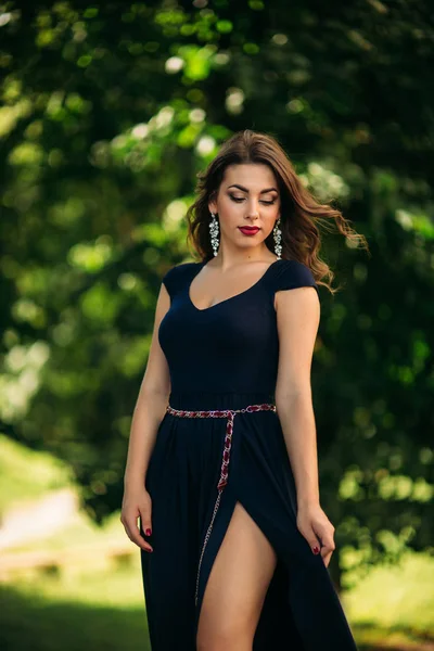 Una bella ragazza con un vestito blu sta camminando nel parco. Soleggiato — Foto Stock