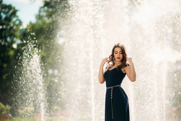 Una chica está caminando por la ciudad, cerca de una gran fuente. Día soleado. Verano — Foto de Stock