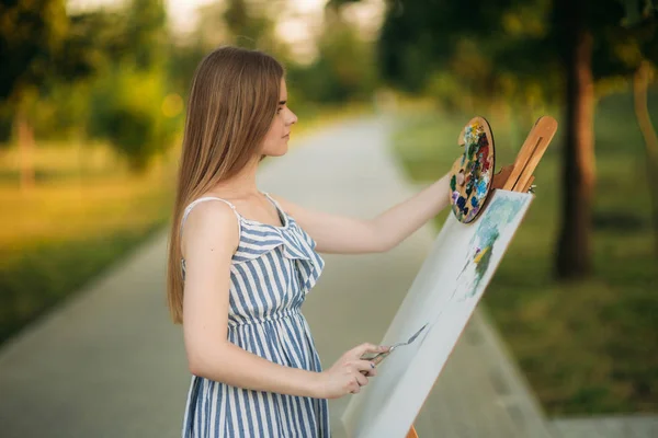 Blond włosy dziewczyna w sukience rysunek obraz w parku — Zdjęcie stockowe