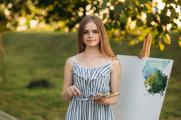Hermosa artista chica está de pie en el parque y la celebración de la paleta con pinturas —  Fotos de Stock