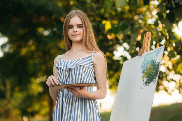 Hermosa artista chica está de pie en el parque y la celebración de la paleta con pinturas —  Fotos de Stock