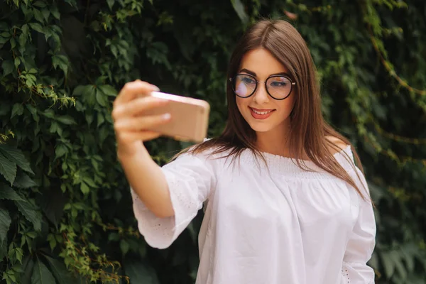 Hermosa chica hacer una selfie en el teléfono inteligente fuera — Foto de Stock