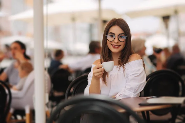 Közelről visel fehér elegáns ruházat és vintage napszemüveg tartó neki reggel cappuccino csésze fehér női divat képe. Érezze jól magát vele egyedül. Instagram színek — Stock Fotó