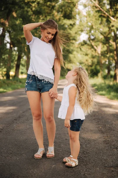 Mother and little daughter walk though the alley and hold each others hands — Stock Photo, Image