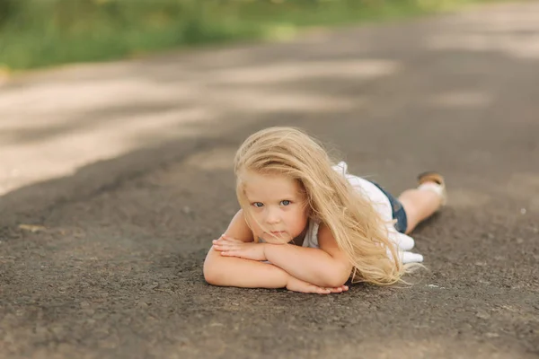Meisje liggen op de weg in de buurt van grote alley — Stockfoto