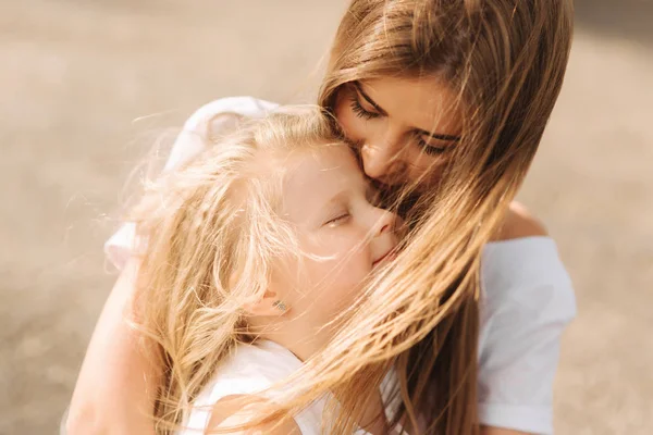 Feliz família amorosa. Mãe e sua filha criança menina brincando e abraçando. beco de árvores grandes. vista de perto — Fotografia de Stock