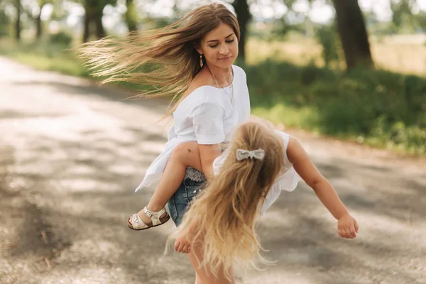 Little girl playing with mom in the park in summer day during the sunset — Stock Photo, Image