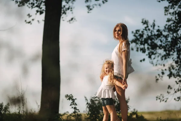 Mother and little daughter walk though the alley and hold each others hands — Stock Photo, Image