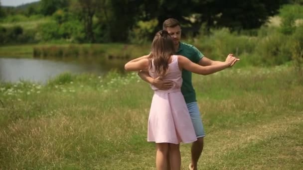 Beautiful couple dance in the field. the enjoy each other and smile. Summer weather. Romantic atmophere. slow motion — Stock Video