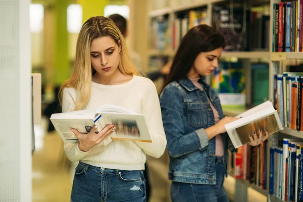 Feliz estudiante chicas jóvenes estudian en la biblioteca — Foto de Stock